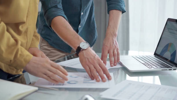 istock Business people, professionals analyzing financial charts and data on a desk while standing and using laptop computer in office 2182022141