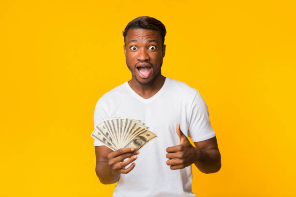 istock Shocked Afro Guy Holding Money Gesturing Thumbs Up In Studio 2182023776