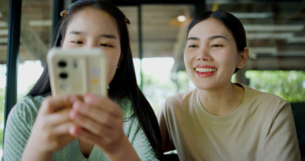 istock Two asian women are enjoy watching something on a mobile phone screen. 2182031111