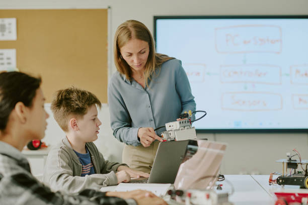 istock School Boy Looking at Robot in Hands of Teacher 2182033556