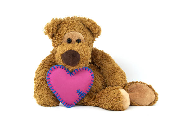 istock Teddy bear holding pink heart with blue stitching, expressing love and warmth on a white background 2182035203