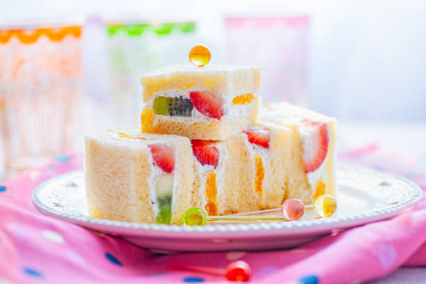 Soft Japanese fruit sandwiches filled with strawberries, kiwi, and whipped cream, garnished with colorful picks