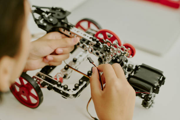High angle shot of unrecognizable female hands holding wires to connect them to unfished robot