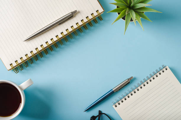 istock Top view of notebook, glasses, coffee and ballpoint pen on blue background 2182043668