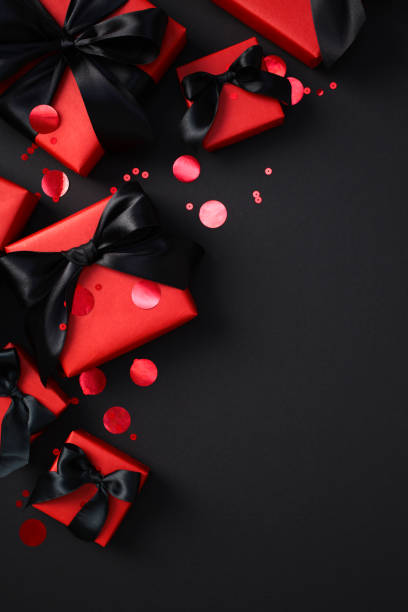 istock Black Friday sale concept. Elegant red gift boxes with black ribbons on a dark background. Flat lay, top view, vertical. 2182043946