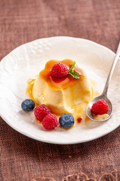 Caramel flan dessert garnished with fresh raspberries, blueberry, and mint