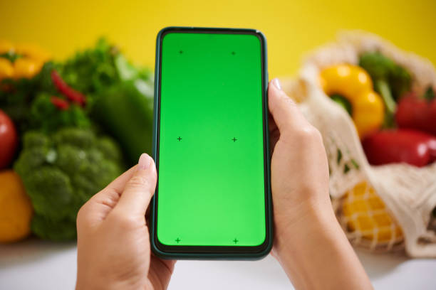 istock Holding Smartphone with Green Screen by Vegetables 2182046611
