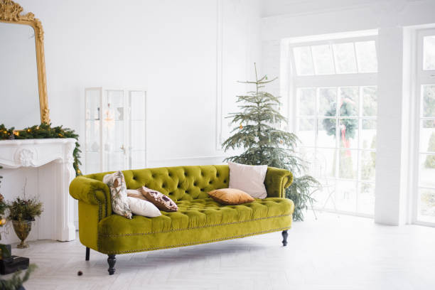 istock The green velour sofa with pillows in the bright attic room has an artificial fireplace.A spacious living room with white walls and a decorated Christmas tree 2182050832