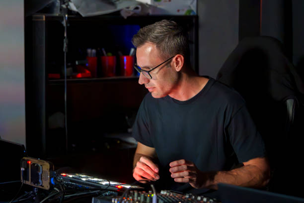 istock Audio Technician Operating a Professional Sound Mixing Console in a Dimly Lit Studio Environment 2182051118