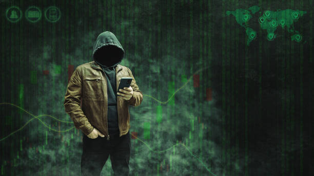 istock Faceless, anonymous hacker in a hoodie and leather jacket standing with a smartphone against a dark background featuring a forex or trading chart. Empty space for text, copy space 2182052091