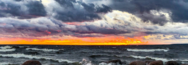istock Dramatic Sunset Over Rocky Shoreline with Dark Clouds and Golden Horizon 2182055370
