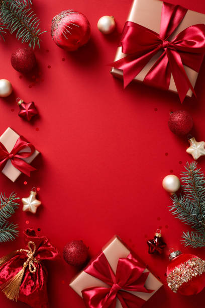 istock Christmas composition. Flat lay gold gift boxes with red ribbon bows, fir branches, and baubles on red background. 2182056875