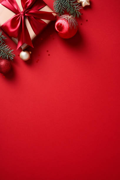 istock Christmas poster with gift box, fir branches and baubles on red background. 2182056987