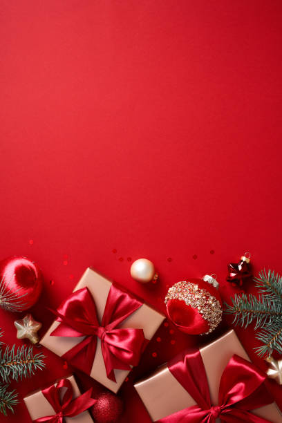 istock Christmas vertical banner design with gift boxes, fir branches and baubles on red background. 2182057096
