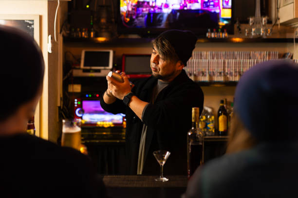 customers sit at bar while bartender serves drinks - 30 40 yaşları arası stok fotoğraflar ve resimler