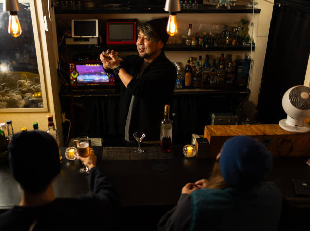 customers sit at bar while bartender serves drinks - 30 40 yaşları arası stok fotoğraflar ve resimler