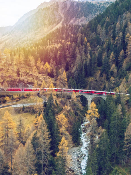istock Red Train Winding Through Autumnal Mountain Scenery 2182063147