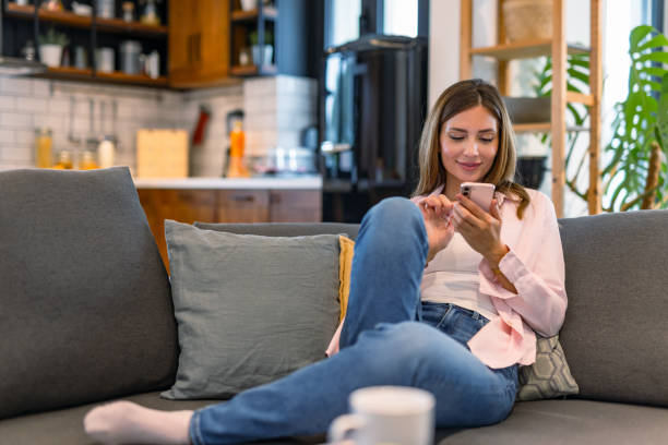istock Relaxed woman using smartphone on cozy couch 2182068051