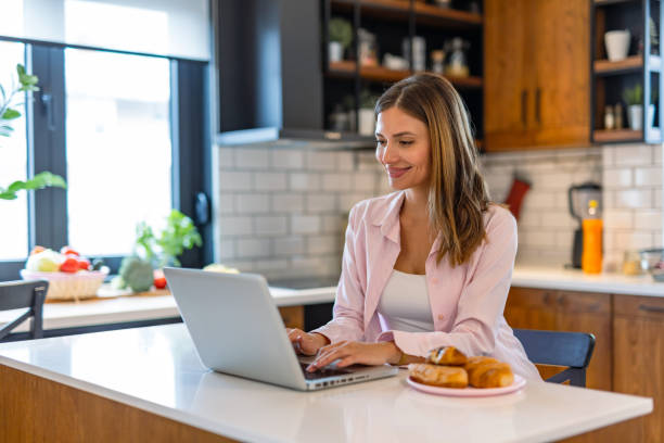 istock Woman works on laptop in stylish kitchen with snacks. 2182068239