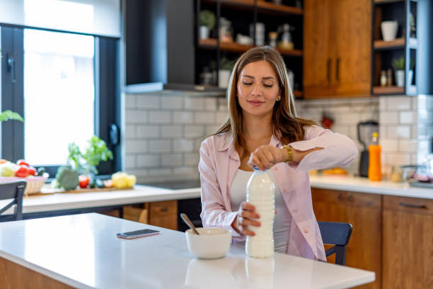 istock Woman prepares milk and cereal in cozy kitchen setting. 2182068321