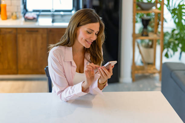 istock Woman engaging with phone in bright kitchen space 2182068392
