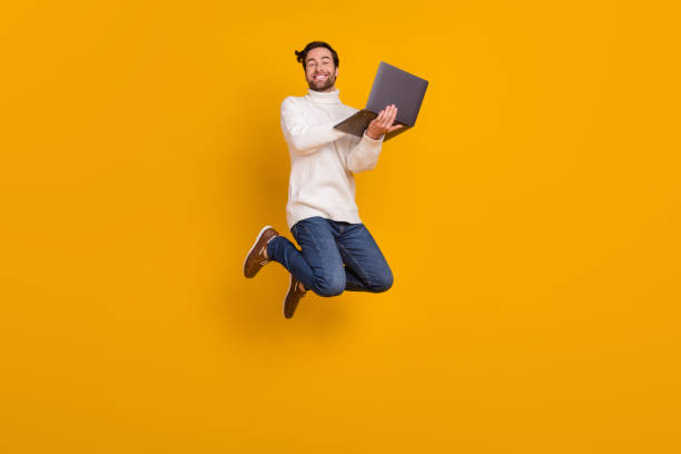 istock Photo of good mood guy wear white pullover jumping high chatting modern device isolated yellow color background 2182069832