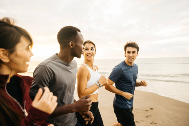 A group of friends enjoys a morning jog on a beach by the sea, showcasing fitness, health, and companionship in an outdoor setting.