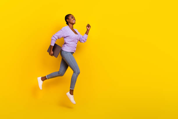 istock Full size profile portrait of excited active lady run jump look empty space hold netbook isolated on yellow color background 2182077900