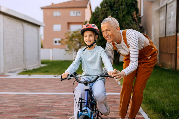 istock Mother supporting her daughter while she is learning how to ride bicycle 2182079422