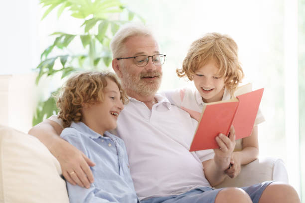 istock Grandfather and kids read book at home. 2182080482