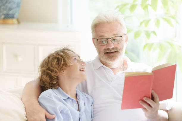 istock Grandfather and kids read book at home. 2182080638