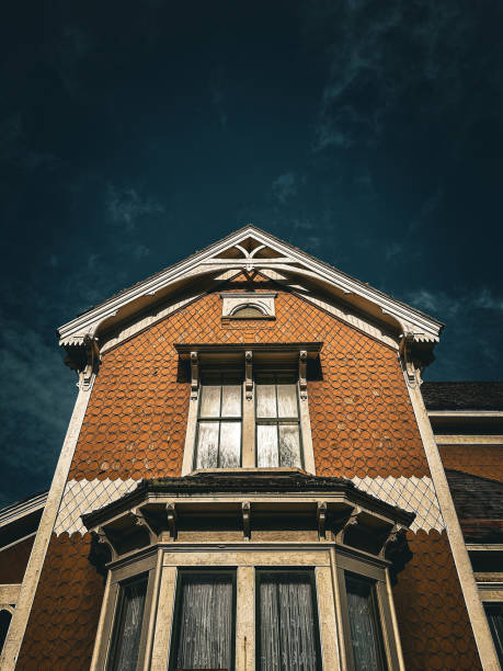A dramatic view of a Victorian-style house with intricate architectural details, set against a dark, moody sky. The rich colors and ornate design elements evoke a timeless and mysterious atmosphere at Hughes Historic House in Cape Blanco State Park, Oregon.
