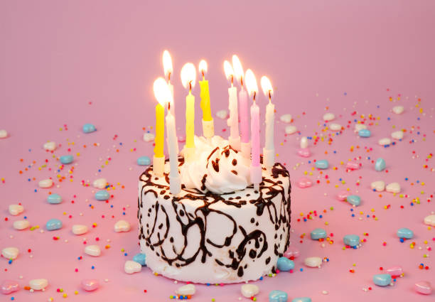 istock Birthday cake with burning candles on pink background 2182091970