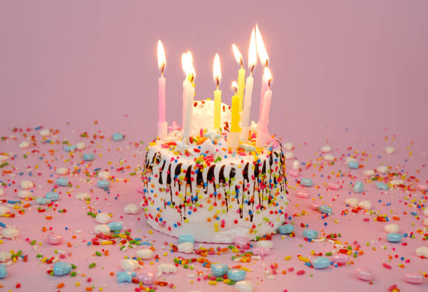 istock Birthday cake with burning candles on pink background 2182091995