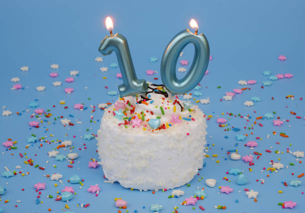 istock Coconut birthday cake on blue background with burning candles, number 10 2182092019