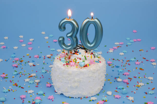 istock Coconut birthday cake on blue background with burning candles, number 30 2182092094