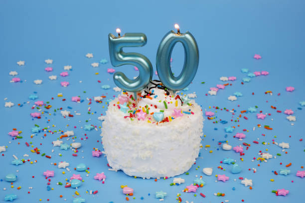 istock Coconut birthday cake on blue background with burning candles, number 50 2182092124
