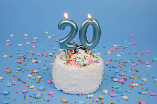 istock Coconut birthday cake on blue background with burning candles, number 20 2182092125