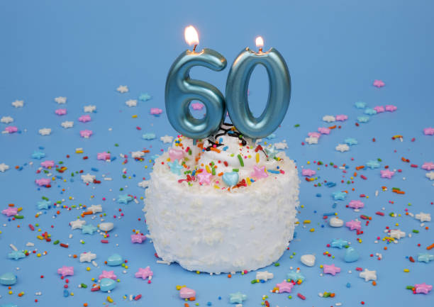 istock Coconut birthday cake on blue background with burning candles, number 60 2182092146