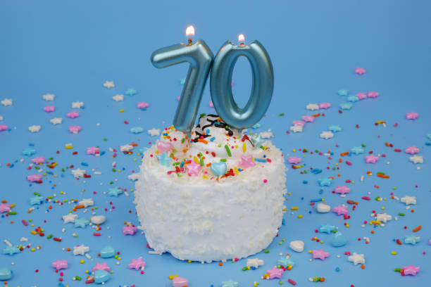 Coconut birthday cake on blue background with burning candles, number 70