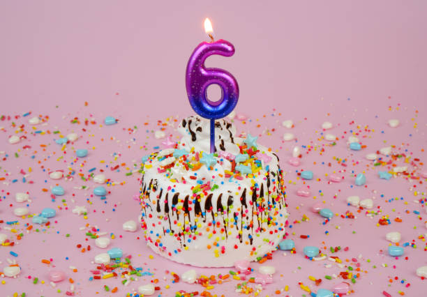 istock Birthday cake with burning candle number 6 on pink background. 2182092265