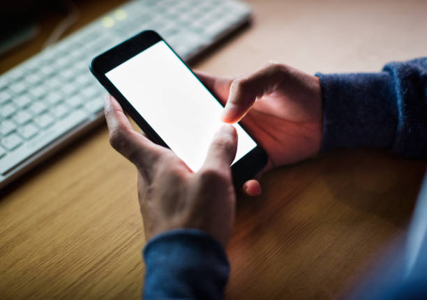 istock Young male tech worker types on his smartphone screen with computers in the background 2182094348
