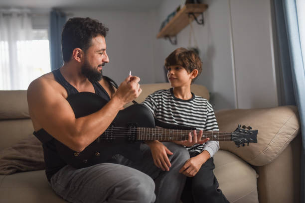 istock Little boy playing electric guitar and learning with dad 2182095668
