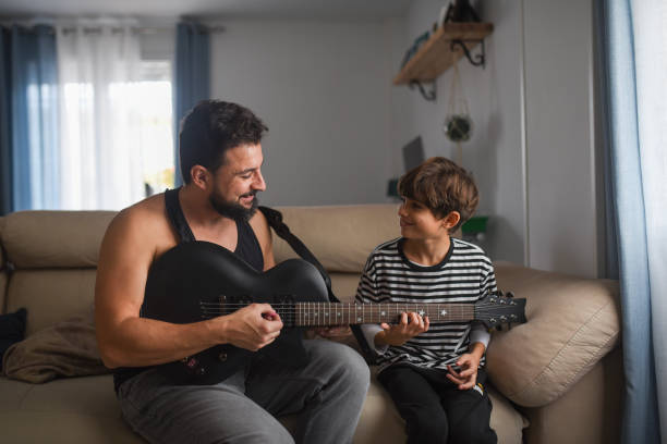 istock Little boy playing electric guitar and learning with dad 2182095675
