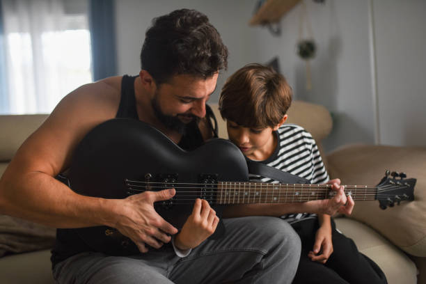 Little boy playing electric guitar and learning with dad