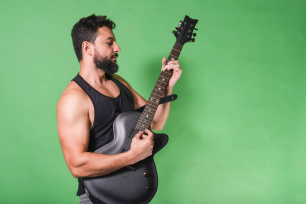 Strong man playing electric guitar in studio shot