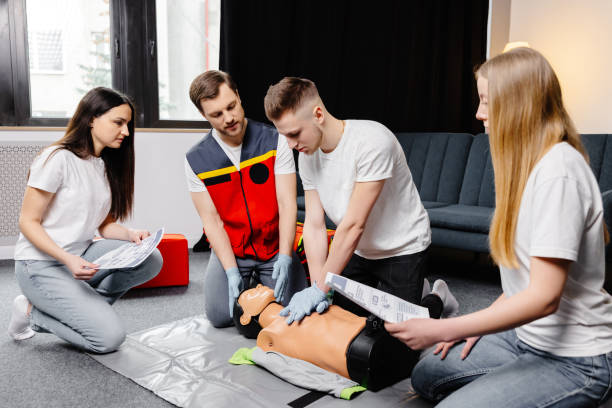 istock Young man instructor helping to make first aid heart compressions with dummy during the group training indoors 2182096330
