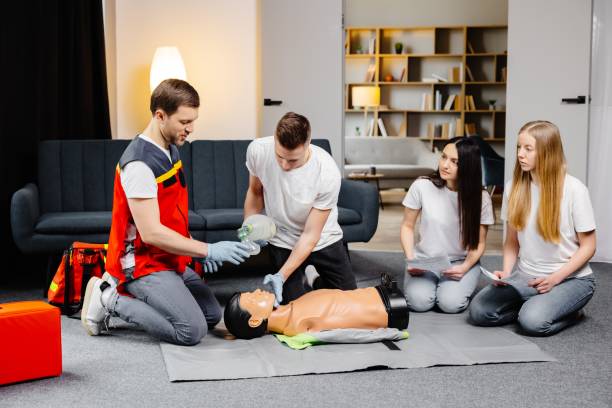 istock Young man instructor helping to make first aid heart compressions with dummy during the group training indoors 2182096333