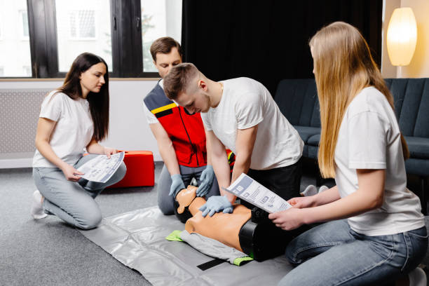 istock Young man instructor helping to make first aid heart compressions with dummy during the group training indoors 2182096375