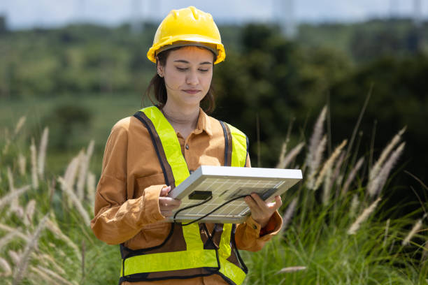 istock Female engineer ecology solar panel plant environment electricity. Alternative innovation energy. woman holding solar panel wind turbines in background. 2182104390